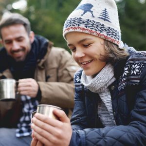 Close up of smiling teenage boy drinking tea in forest